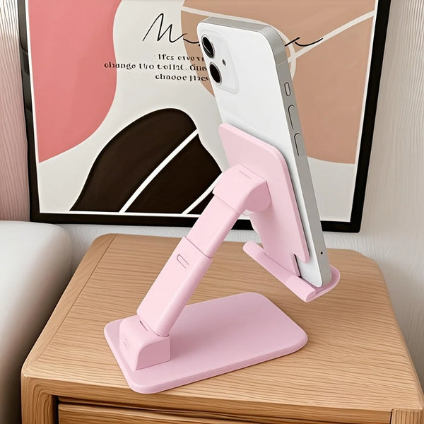 A pink adjustable desktop phone stand holding a smartphone in a vertical position on a wooden table.