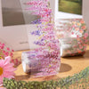 Transparent floral vine washi tape featuring pink and purple blossoms used for journaling and crafts.