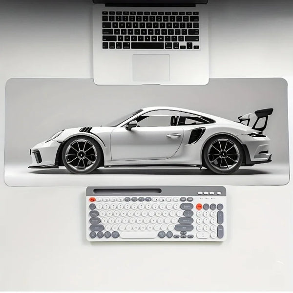 Un coche deportivo blanco exhibido en una alfombrilla de ratón de juego con una laptop y teclado de fondo.