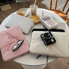 A white laptop sleeve case is shown on a table with various accessories like glasses and a notebook.