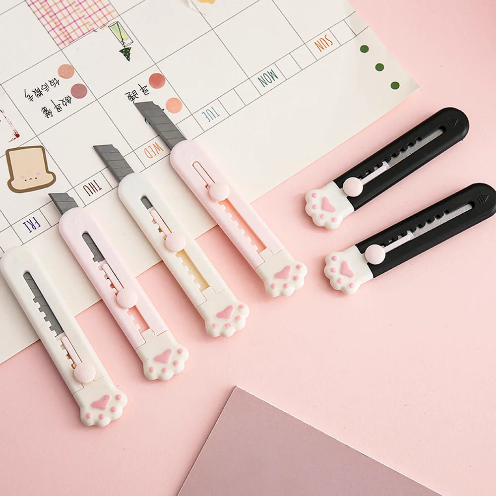 A collection of pink and black portable pet claw tools or knives laid on a pink calendar page.