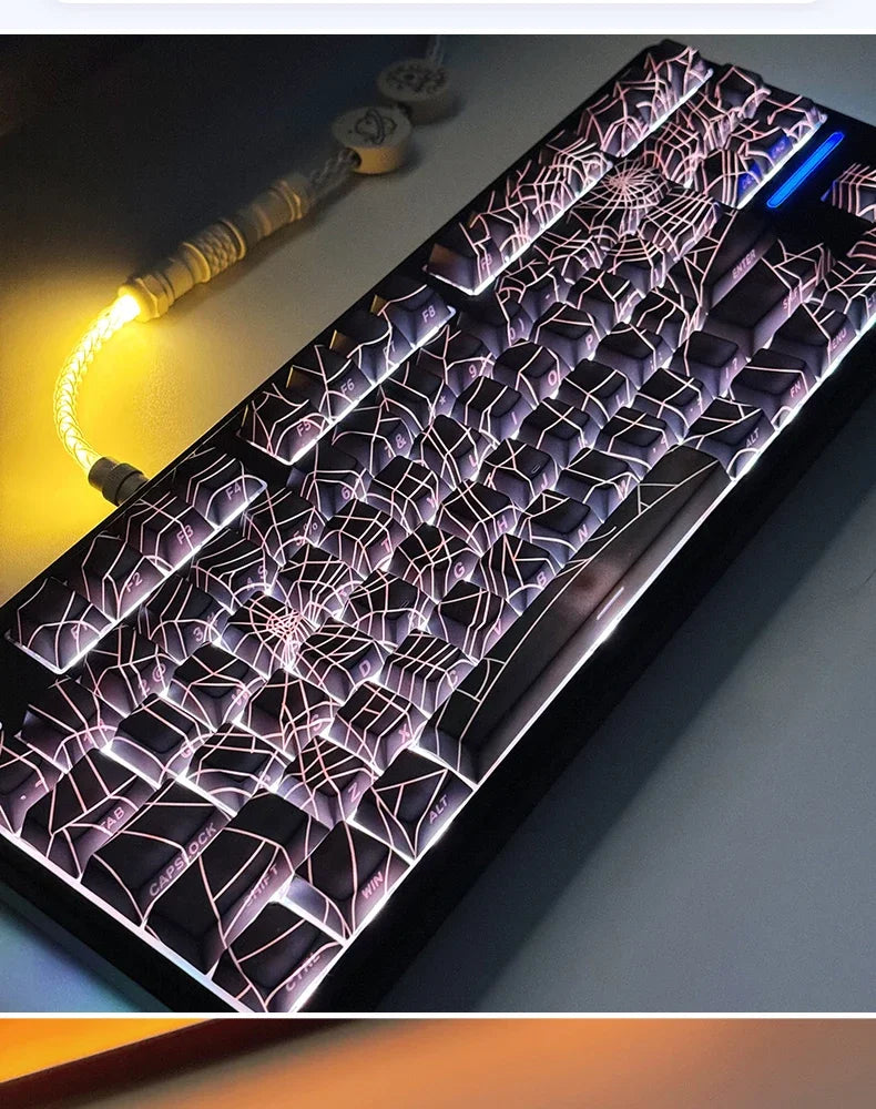 A close-up view of a mechanical keyboard with translucent keycaps featuring a spiderweb design and glowing purple lighting.