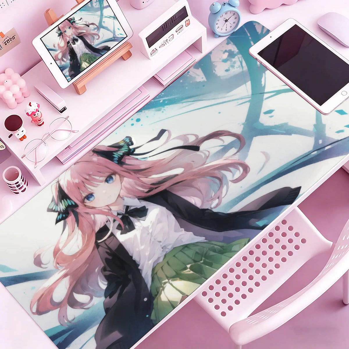 A pink anime girl illustration on a large desk mat next to a white tablet and mouse pad.