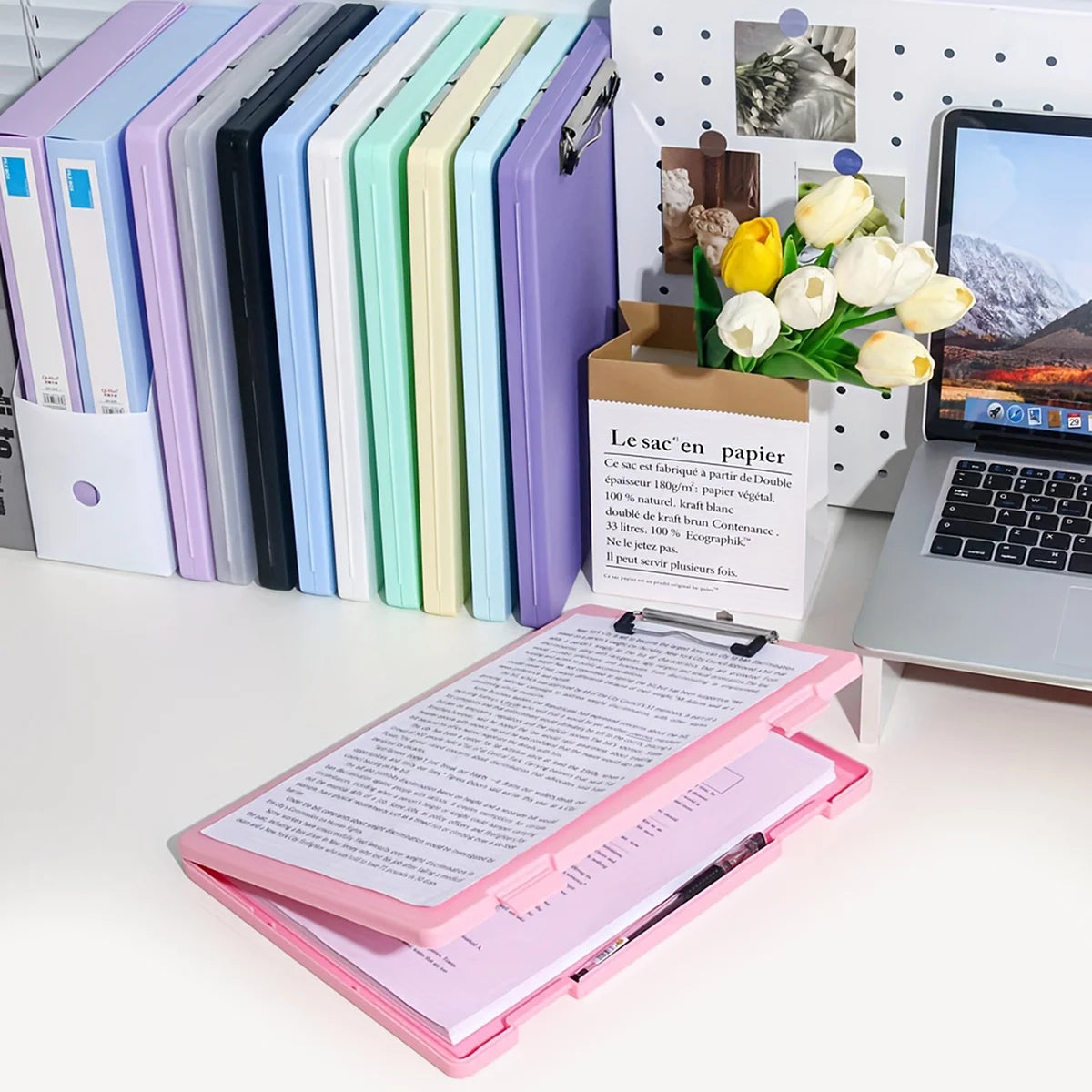 A set of colorful A4 document and photo storage file boxes lined up next to a laptop and a pink file folder.