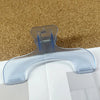 Clear plastic book page clips with a curved shape resting on a brown textured surface.