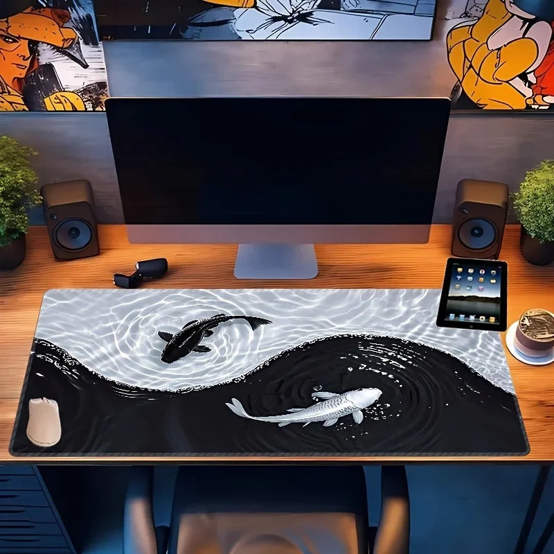 A black and white koi fish pattern non-slip gaming mouse pad placed on a wooden desk in front of a computer monitor.