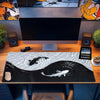 A black and white koi fish pattern non-slip gaming mouse pad placed on a wooden desk in front of a computer monitor.