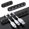 A set of silicone cables and connectors organized in a black plastic holder on a dark surface.