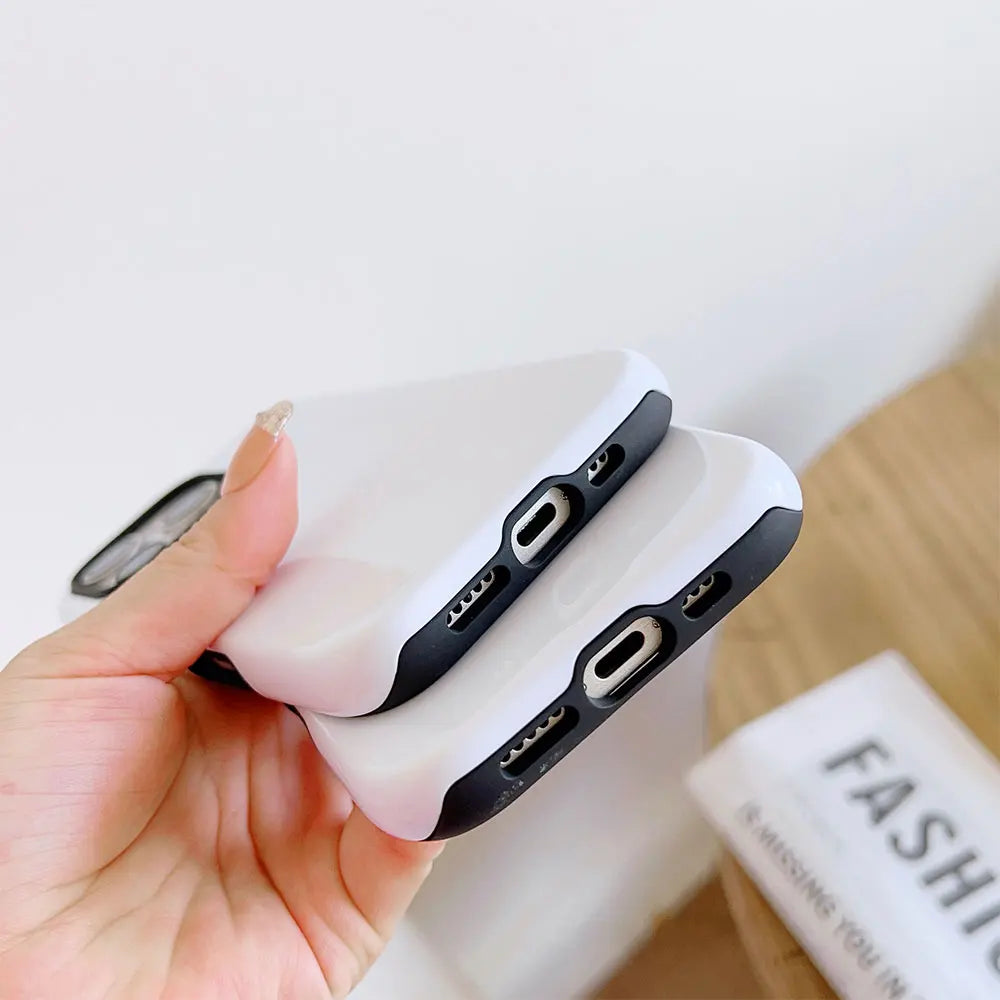 A hand holds a white dual-layer phone case with black accents against a light background.