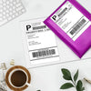 A purple thermal shipping label is shown on a white sheet, next to a laptop and a cup of coffee.