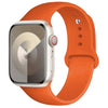 An Apple Watch in a silver case with an orange silicone sport band.