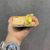 A hand holds a yellow phone case with a yellow snake lanyard against a gray background.
