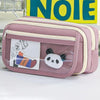 A pink pencil case with a transparent flip pocket featuring a panda charm and an illustration.