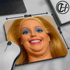 A close-up of a blonde doll face printed on a mouse pad with measurements and a computer mouse nearby.