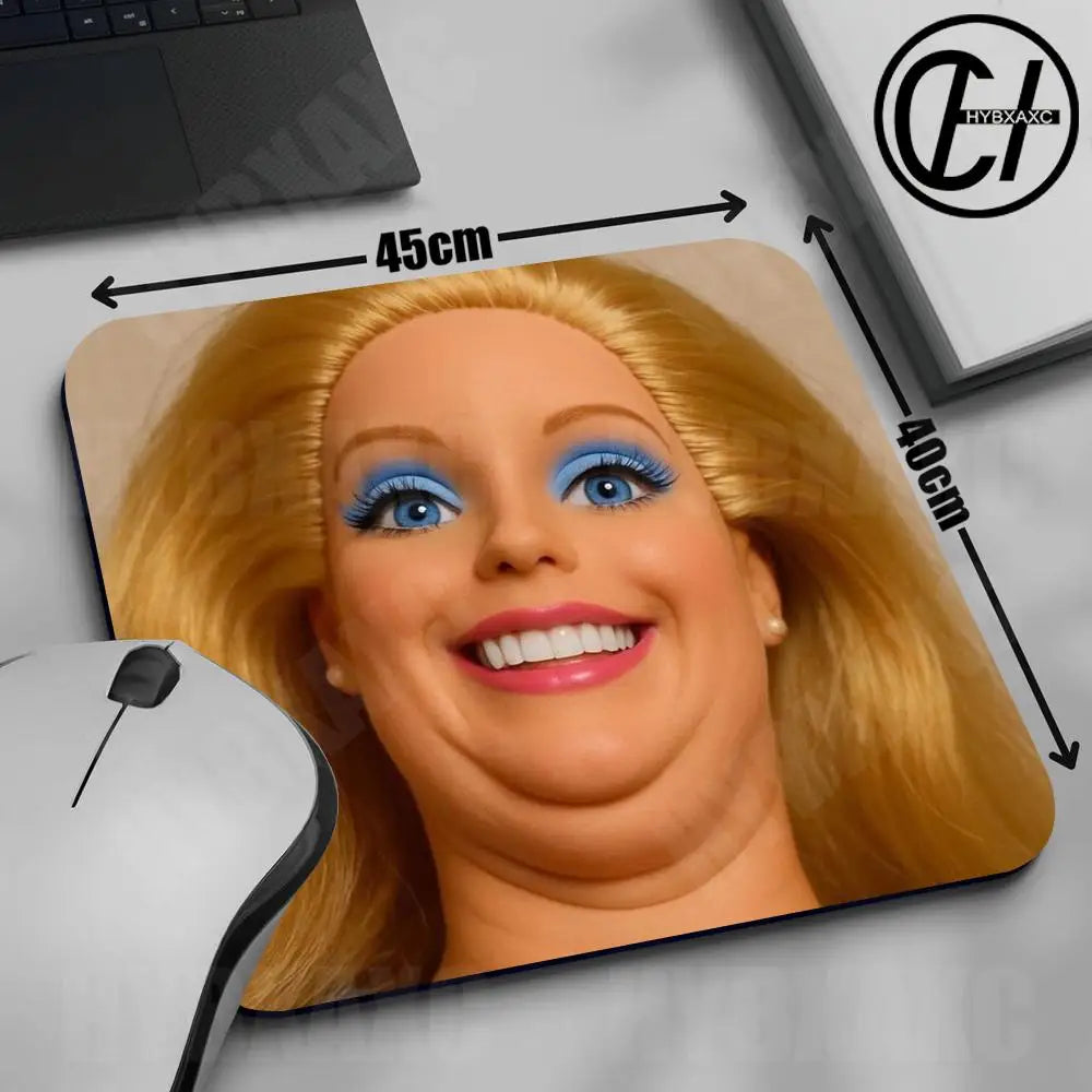 A close-up of a blonde doll face printed on a mouse pad with measurements and a computer mouse nearby.