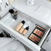 A clear acrylic drawer organizer set containing various makeup and cosmetic products.