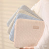 A stack of beige and light blue laptop sleeves is held by a person.