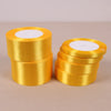 Two stacks of gold yellow satin ribbon rolls with white centers