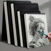 A set of black and white spiral notebooks and a sketchbook featuring a pencil drawing of a woman's profile.