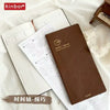 A brown weekly planner journal with handwritten and printed layouts is shown on a white background.