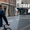 Un hombre de traje azul lleva una mochila de laptop negra mientras pedalea en una calle de la ciudad.