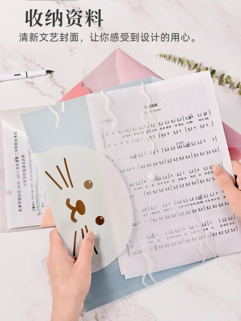 Hands are holding a set of four transparent document pouches with cartoon designs on a white marble surface.