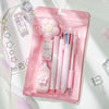 A pink plastic pouch containing a cute cartoon school stationery set including pens and accessories.