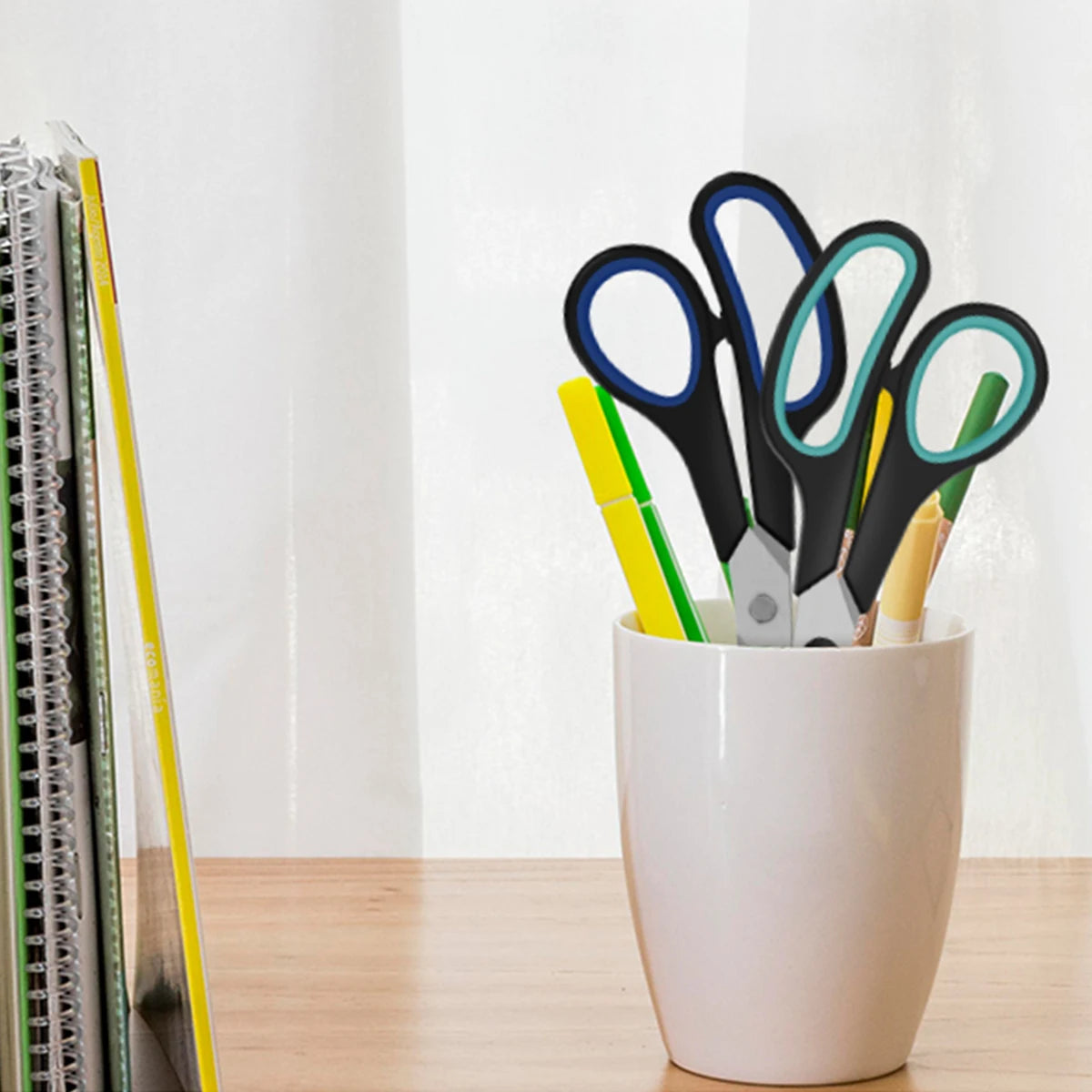 A set of black and colored stainless steel scissors displayed in a white pot.