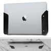 A silver laptop is mounted on an under-desk clamp with black silicone padding.