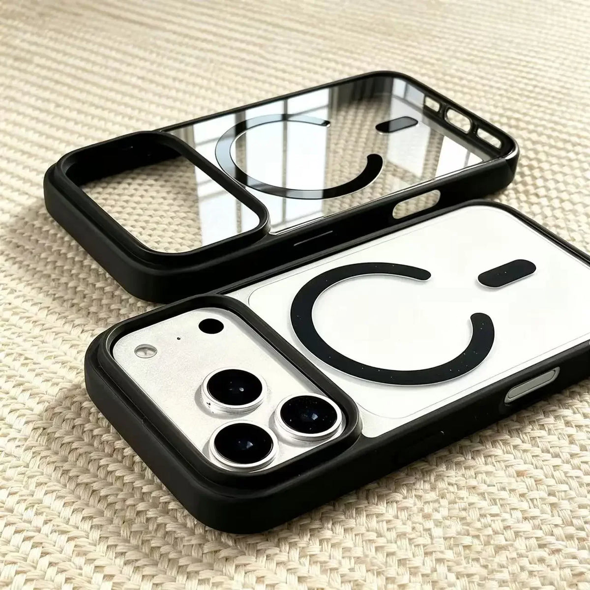 A transparent acrylic phone case with a black frame and a cutout design is shown on a light textured surface.