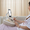 A woman uses a 360° rotatable phone and tablet stand for viewing while relaxing.