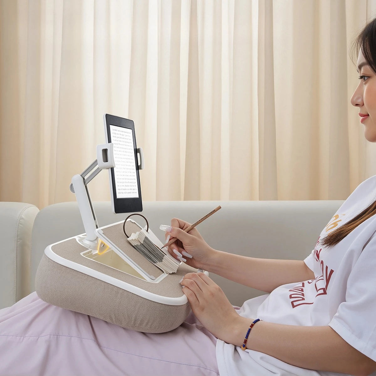 A woman uses a 360° rotatable phone and tablet stand for viewing while relaxing.