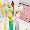 A set of colorful beaded ballpoint pens featuring heart and butterfly designs displayed in a white container.