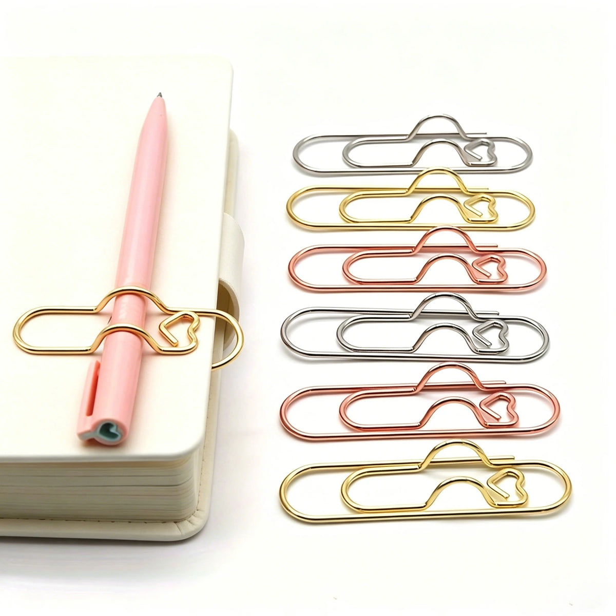 A set of gold and silver magnetic pen clips used as page markers, displayed next to a pink pen.