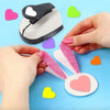 Una mano usa una herramienta punzonadora de corazón para crear una forma de corazón en papel para scrapbooking.
