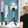 A pink extendable Bluetooth selfie stick with a built-in fill light is shown next to a white version and a smartphone.