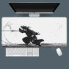 A black and white illustration of a warrior in a dynamic pose on a gaming mousepad with a computer monitor and keyboard.
