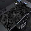Extra large abstract desk mat with white line design placed on a dark gray desk.