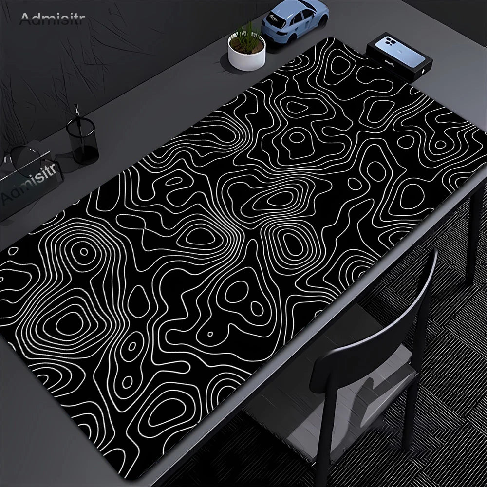 Extra large abstract desk mat with white line design placed on a dark gray desk.