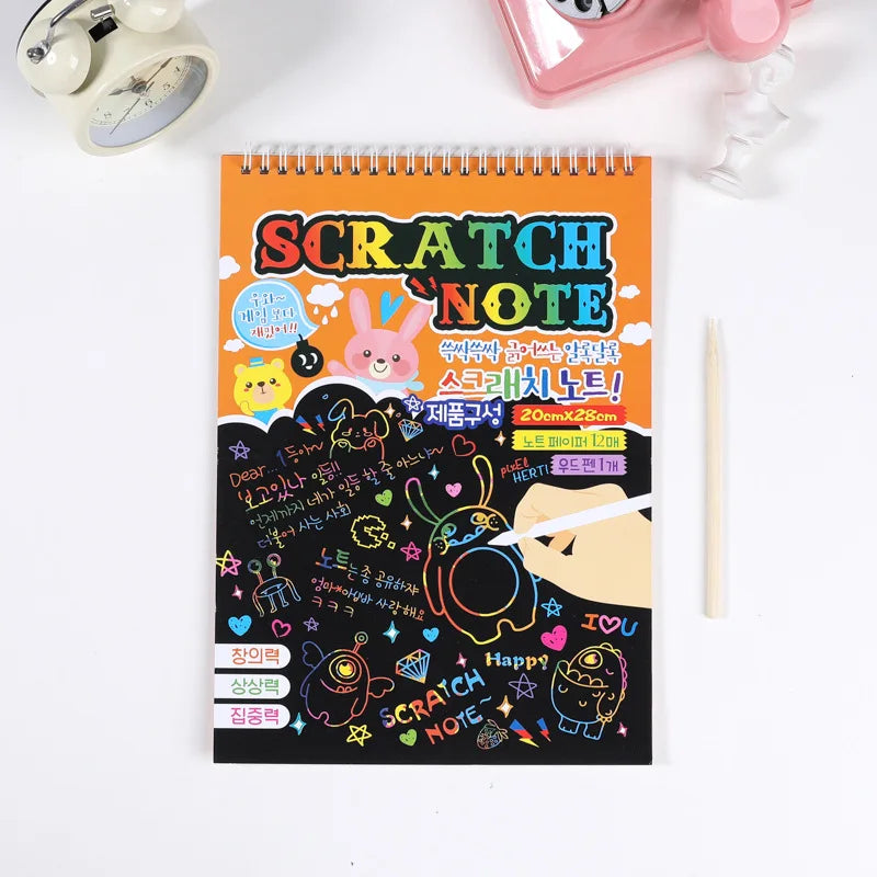 An orange spiral notebook titled Scratch Note featuring cute characters and text, with a pencil resting beside it.