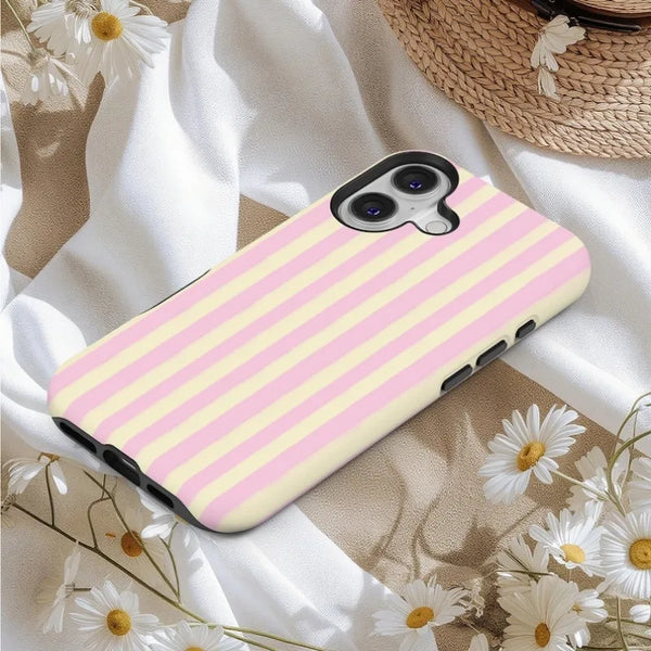 A pink and yellow striped magnetic dual-layer phone case for an iPhone resting on a white fabric with flowers.
