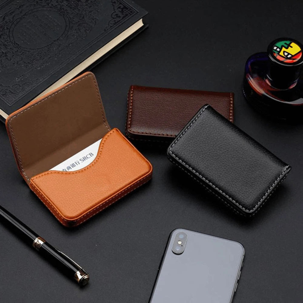 Colección de carteras de cuero sintético PU marrón y negro cosidas, un bolígrafo y un smartphone sobre una superficie oscura.