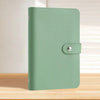 A green reusable binder with a silver clasp is shown on a wooden surface.