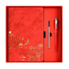 A red box containing a luxury notebook set with a silver pen inside.