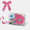 A pink Barbie pin bow and a clear label maker device with pink rollers and a pink ribbon.