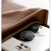 A close-up of a magnetic wireless charger with a stand placed on a laptop next to an iPhone.
