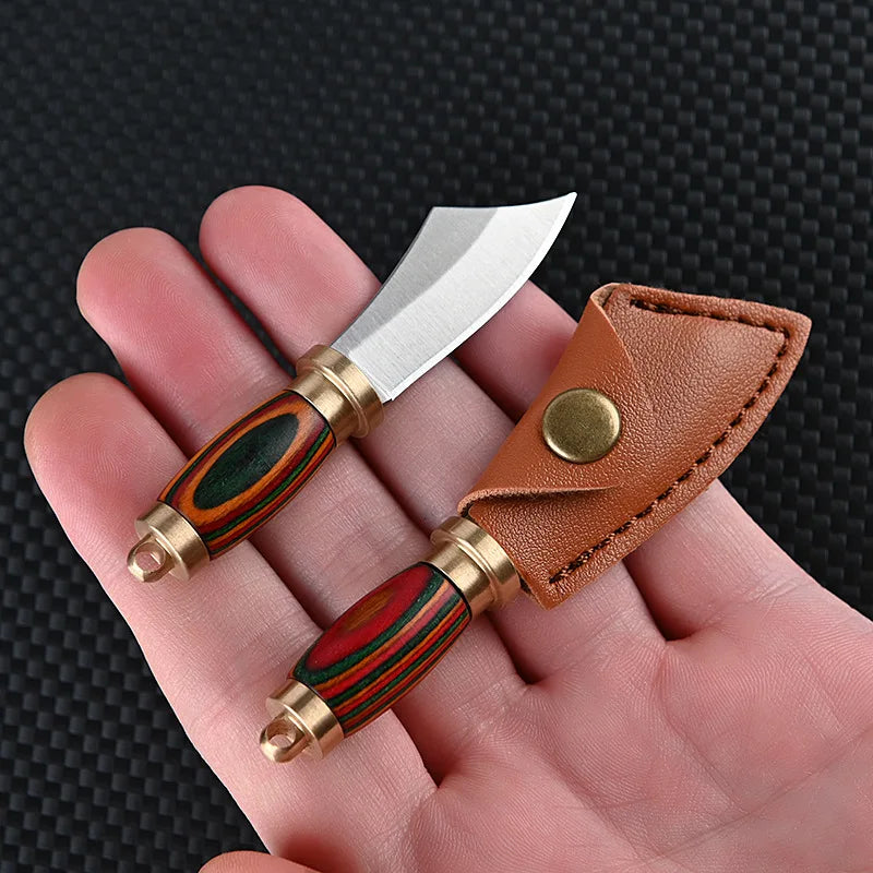 A compact fixed blade knife with a silver blade and wooden handle is shown in a brown leather sheath being held in a hand.