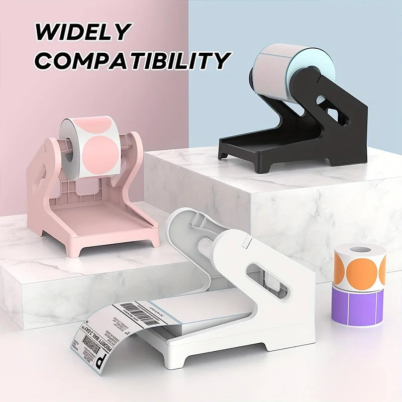 A pink and white 2-in-1 thermal label holder is shown with rolls of labels and fan-folded labels on a white marble surface.