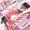 A close-up of a pink-haired anime character illustration on a mouse pad and desk mat with various stationery items.