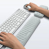 A hand rests on a light gray ergonomic keyboard and mouse with a matching wrist rest pad.